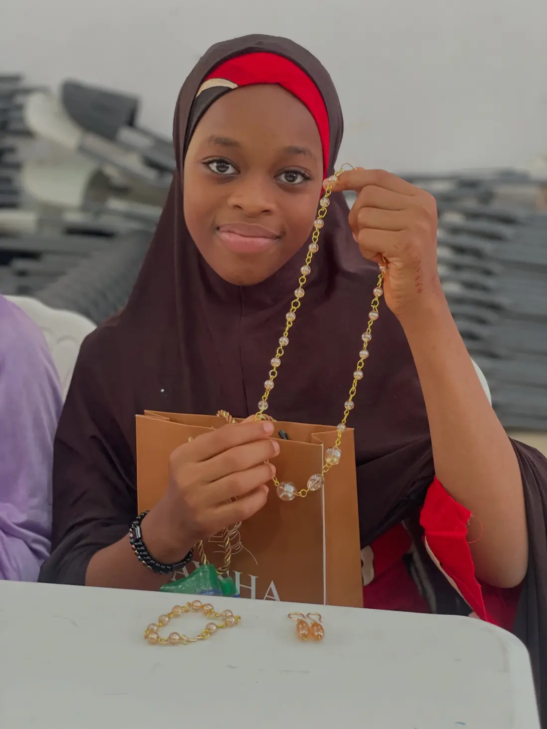 A participant holds up a beaded chain she made during ABI training